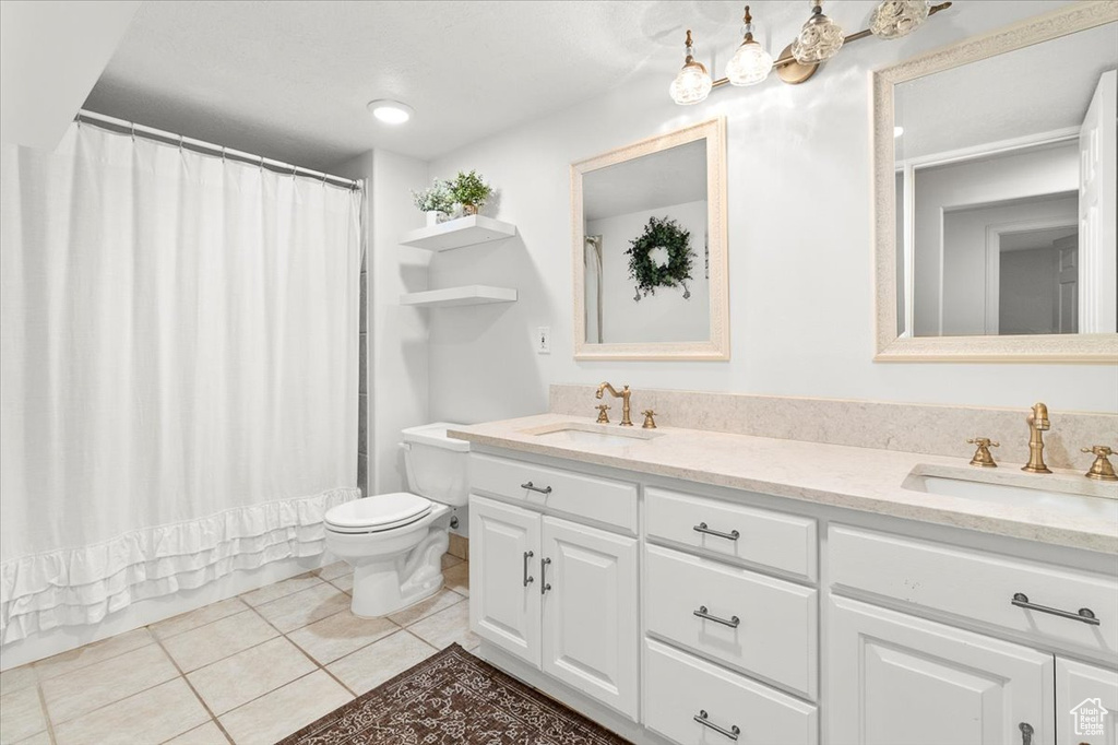 Full bathroom featuring double vanity, toilet, tile patterned flooring, and a sink