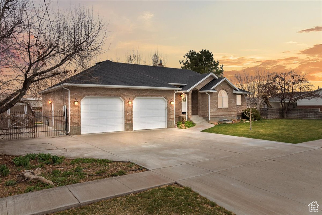 Ranch-style home with an attached garage, concrete driveway, brick siding, and a front yard