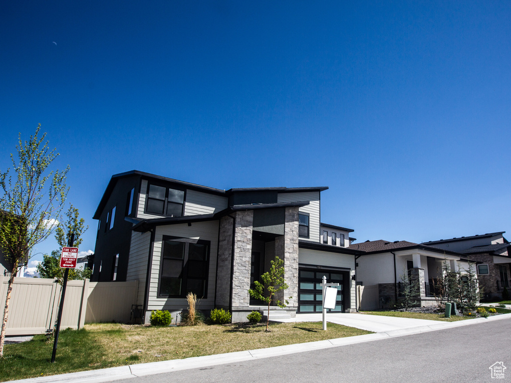 View of front facade featuring stone siding, an attached garage, and concrete driveway