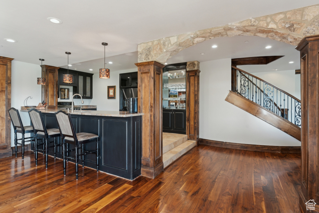Kitchen featuring dark wood-style floors, baseboards, a kitchen bar, a peninsula, and light stone counters