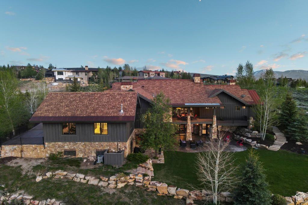 Back of property with a patio area, a chimney, a lawn, a mountain view, and stone siding