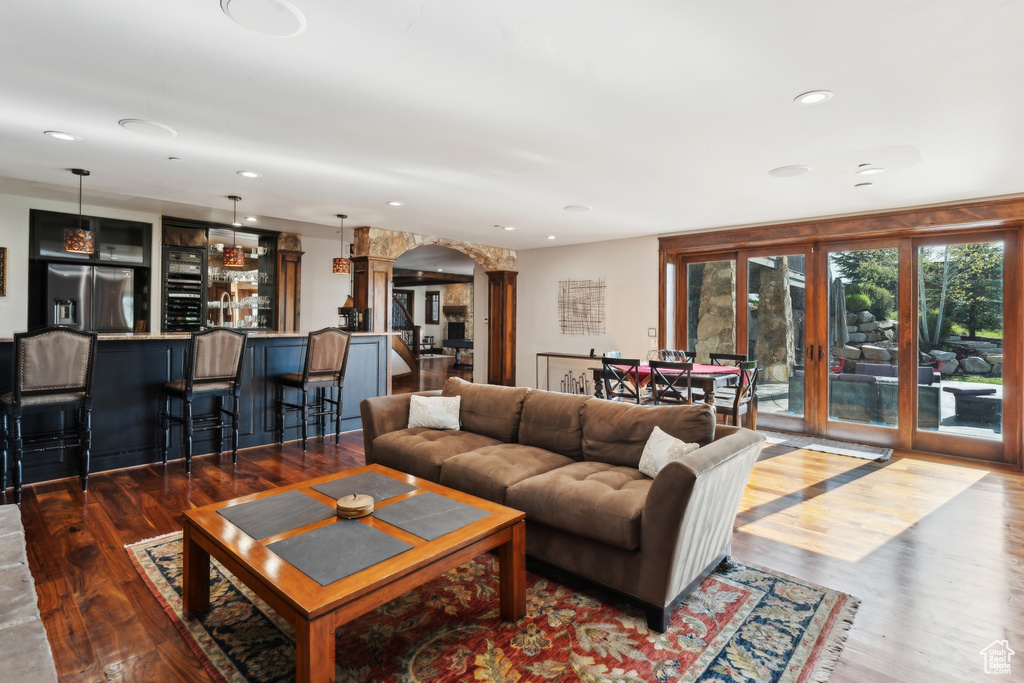 Living room with arched walkways, wood finished floors, bar, recessed lighting, and french doors