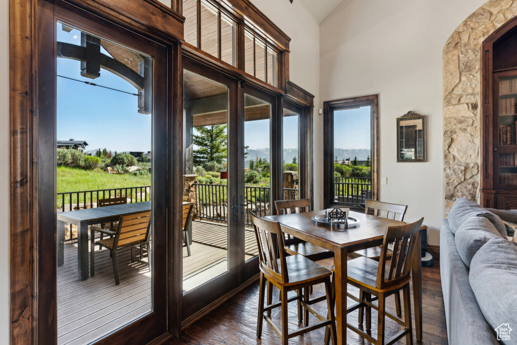 Dining room with plenty of natural light, dark wood-style flooring, and a high ceiling