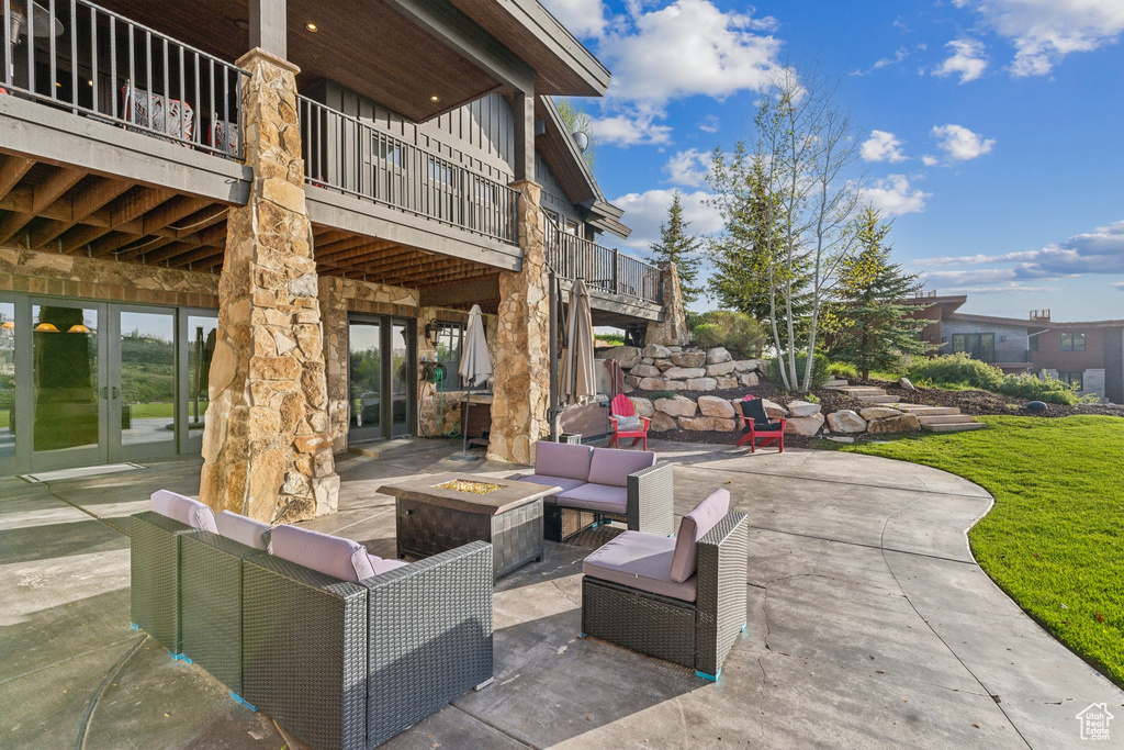 View of patio / terrace with french doors, an outdoor living space with a fire pit, and a balcony