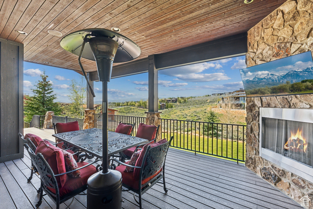 Deck with a lit fireplace and outdoor dining area