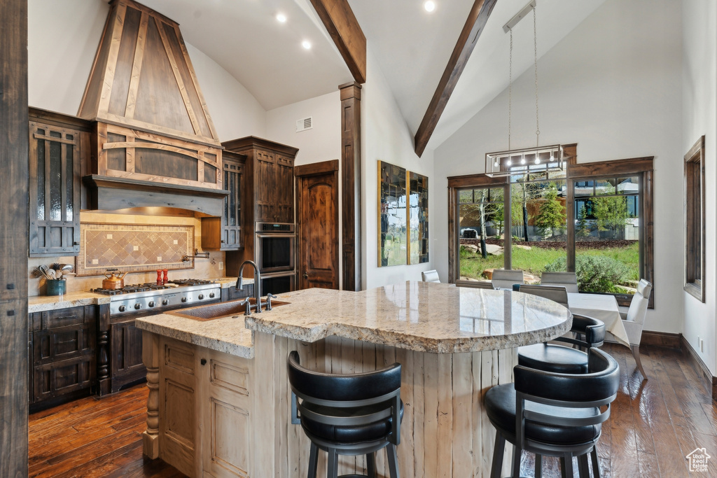 Kitchen featuring a sink, appliances with stainless steel finishes, backsplash, a kitchen island with sink, and a kitchen breakfast bar