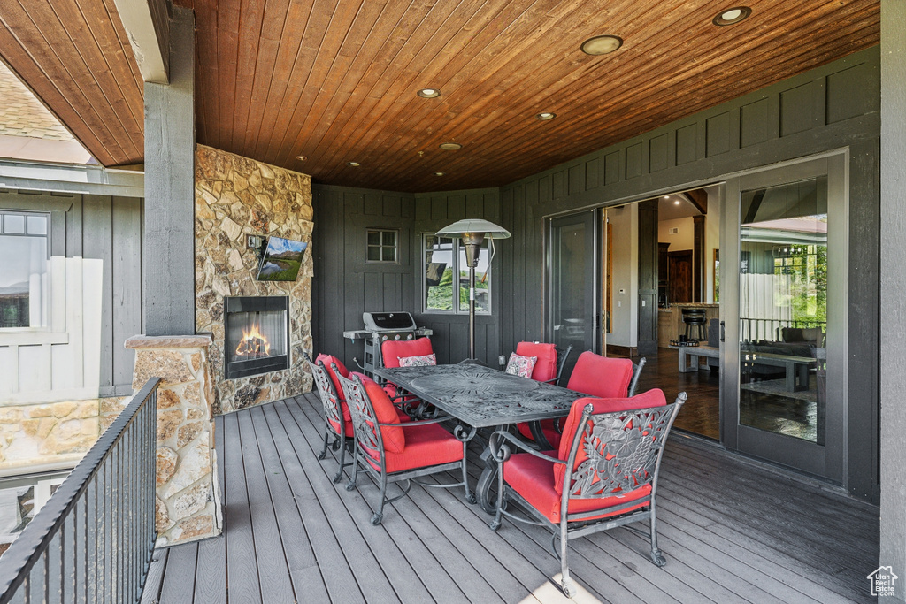 Wooden deck with an outdoor stone fireplace and outdoor dining space