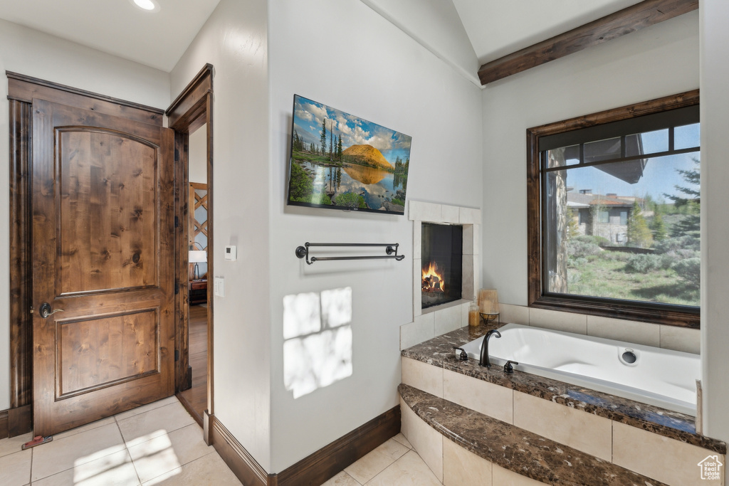 Full bath with a bath, tile patterned floors, healthy amount of natural light, and vaulted ceiling