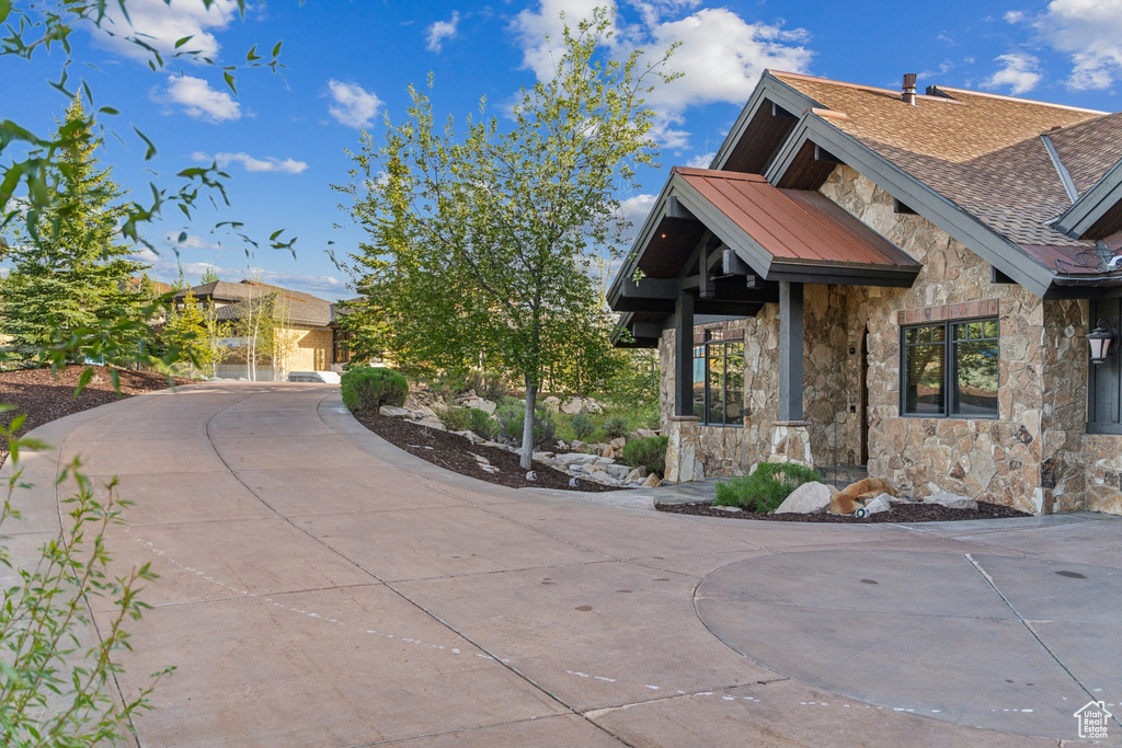 View of side of home featuring stone siding and curved driveway