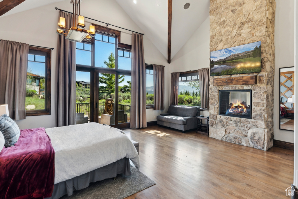 Bedroom featuring a fireplace, high vaulted ceiling, and wood finished floors