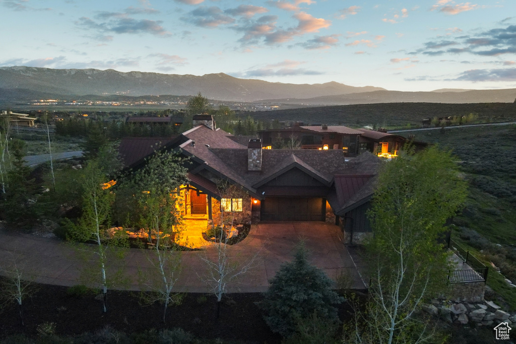 View of front of property featuring a mountain view, a chimney, driveway, a garage, and stone siding