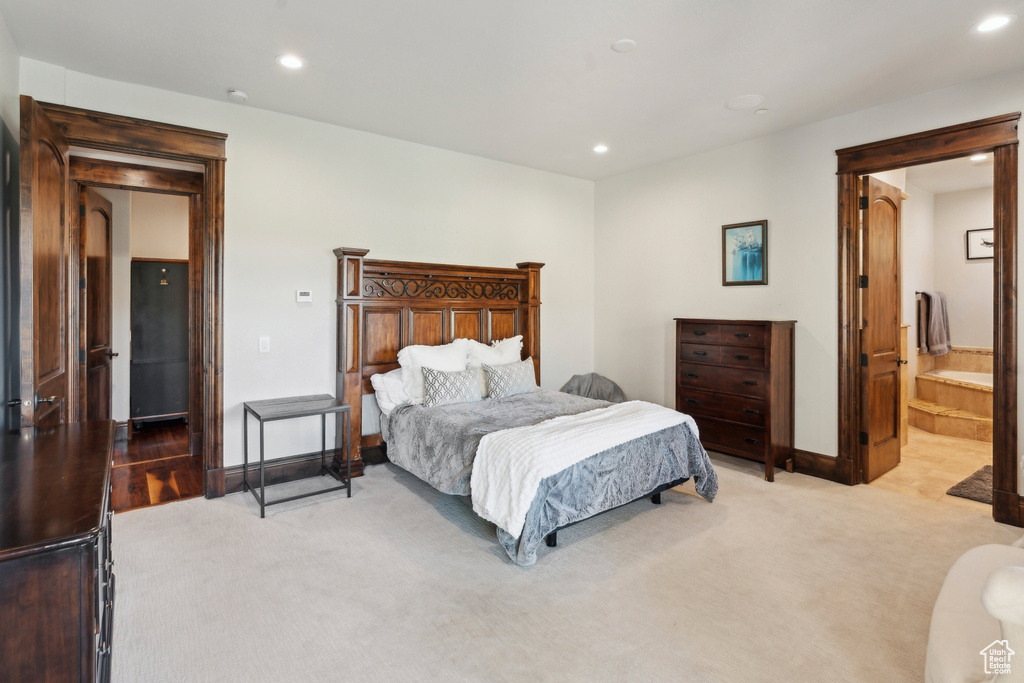 Bedroom with light colored carpet, recessed lighting, baseboards, and connected bathroom