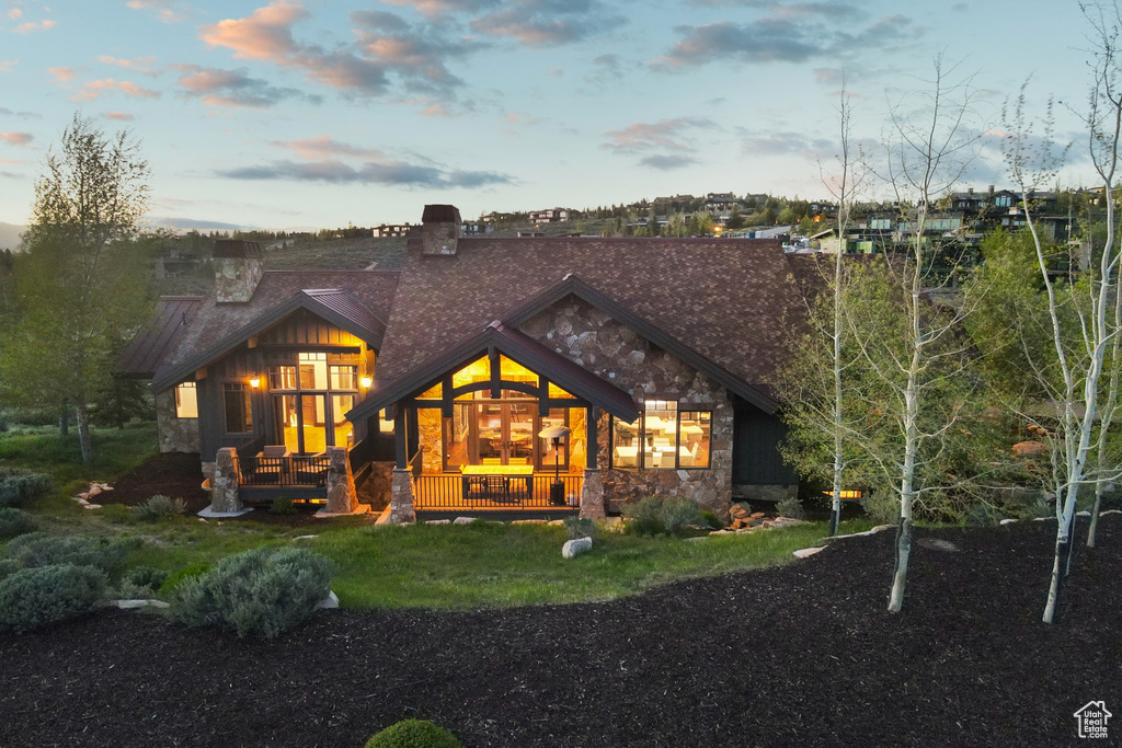 Rear view of property featuring stone siding and a chimney