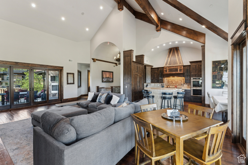 Living area with high vaulted ceiling, beam ceiling, arched walkways, dark wood-style floors, and recessed lighting