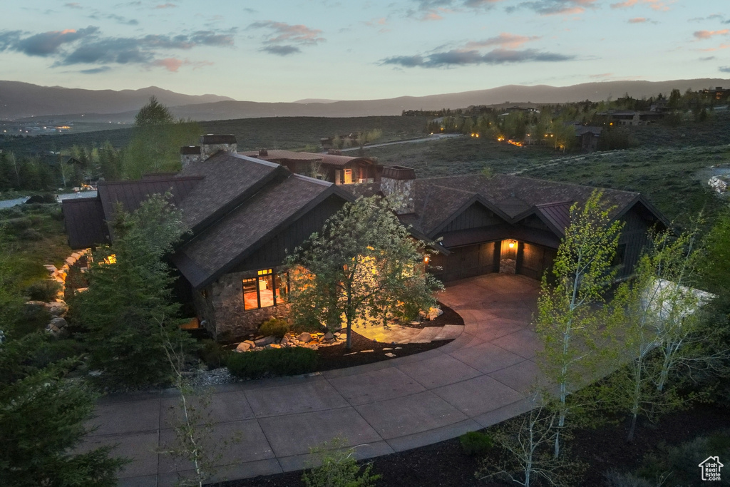 View of front of home featuring a mountain view, a chimney, stone siding, and roof with shingles