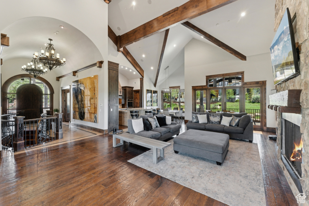 Living area with high vaulted ceiling, arched walkways, beam ceiling, a large fireplace, and hardwood / wood-style flooring