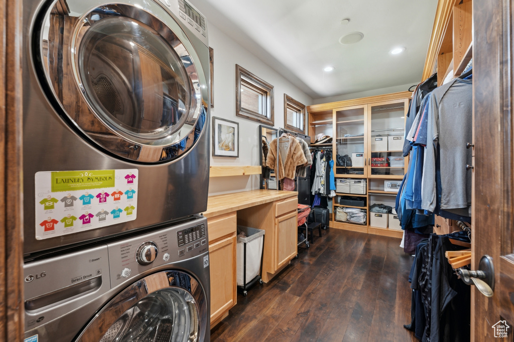Washroom featuring stacked washing machine and dryer, dark wood-style floors, and recessed lighting