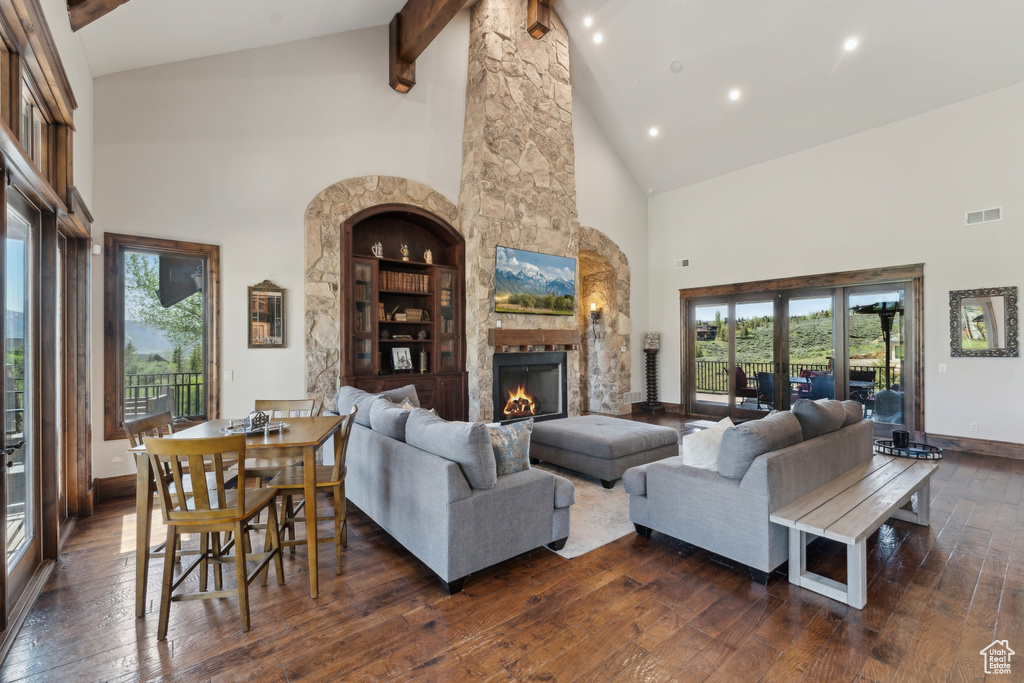 Living room with high vaulted ceiling, dark wood finished floors, beam ceiling, plenty of natural light, and baseboards