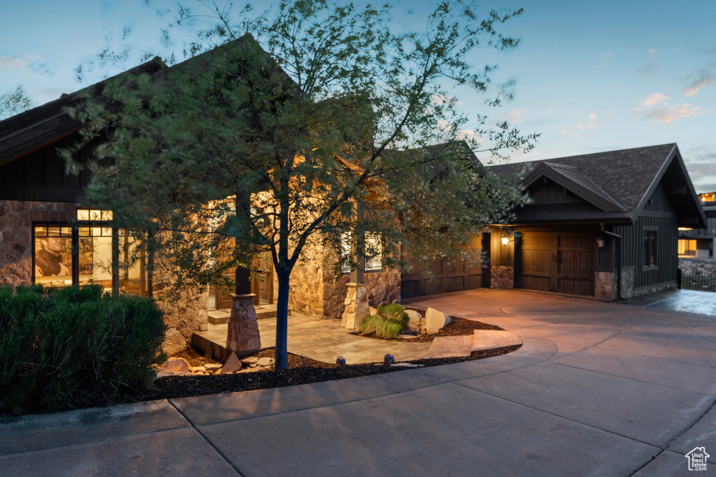 View of front of property featuring stone siding, concrete driveway, board and batten siding, and an attached garage