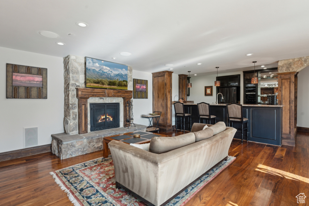 Living area with dark wood finished floors, a fireplace, recessed lighting, baseboards, and wet bar