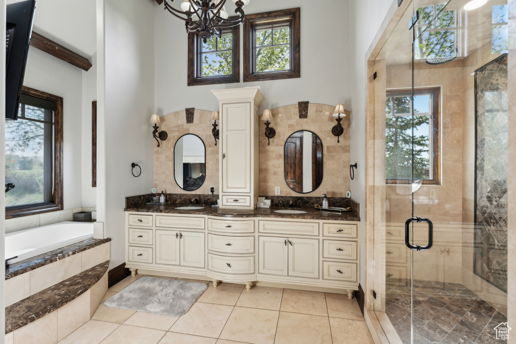 Full bath with double vanity, healthy amount of natural light, and a shower stall
