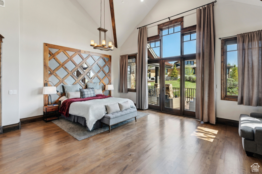 Bedroom featuring high vaulted ceiling, access to exterior, wood finished floors, and baseboards