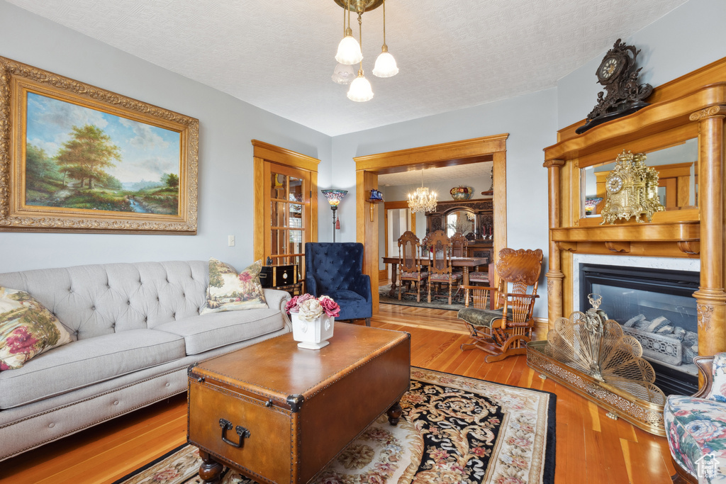 Living room featuring an inviting chandelier, a glass covered fireplace, and wood finished floors