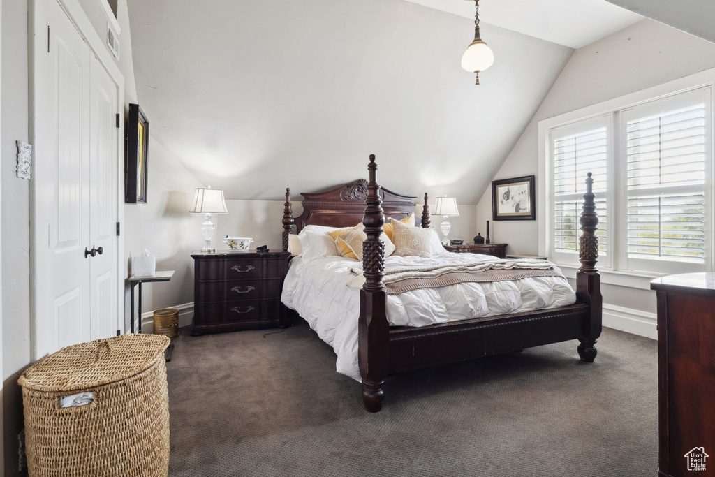 Bedroom with dark carpet, a closet, lofted ceiling, and baseboards