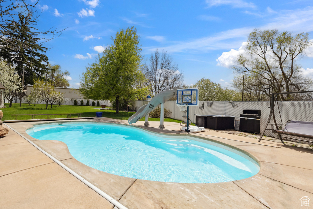 View of swimming pool with a yard, a water slide, a patio area, and a fenced in pool