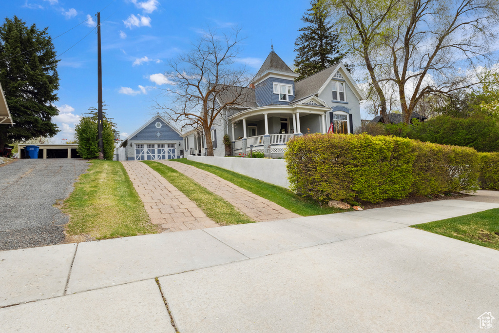 Victorian house with a porch, a detached garage, and aphalt driveway