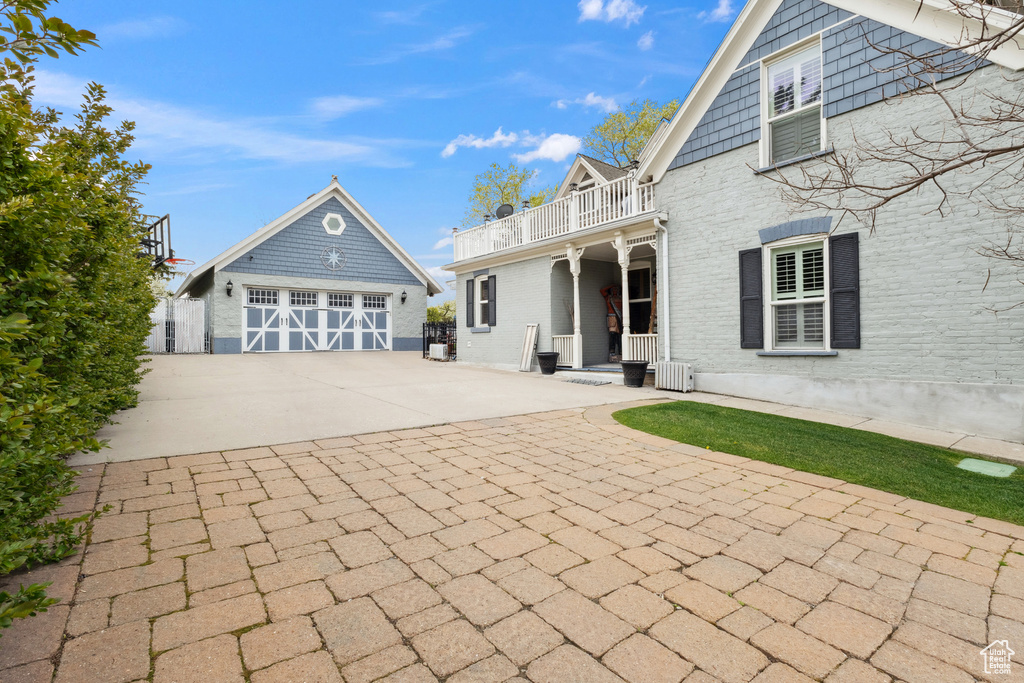 View of front of home featuring brick siding, a balcony, an outbuilding, and driveway