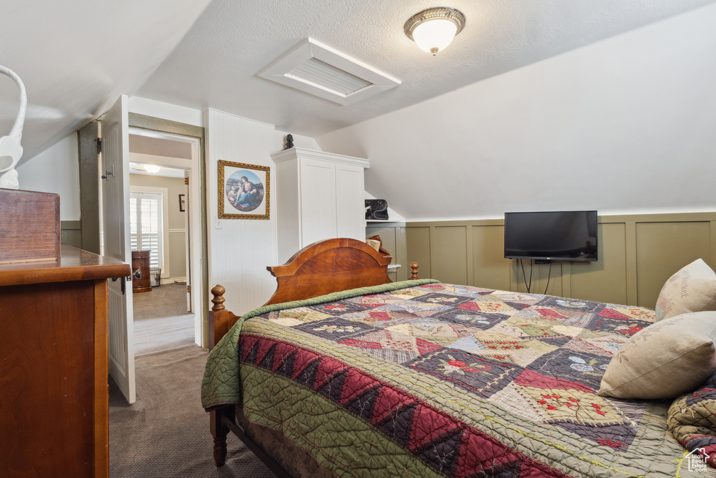Carpeted bedroom with vaulted ceiling and a decorative wall