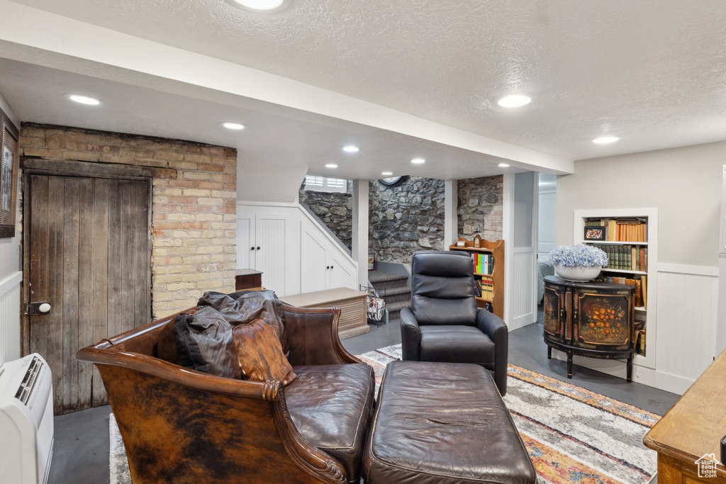 Living area featuring stairs, a decorative wall, a wainscoted wall, finished concrete flooring, and a textured ceiling