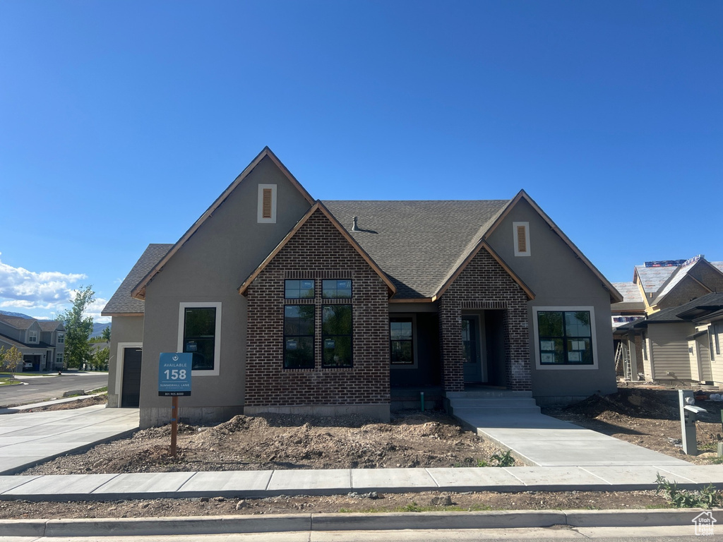 Craftsman-style house featuring concrete driveway, brick siding, a shingled roof, and a garage