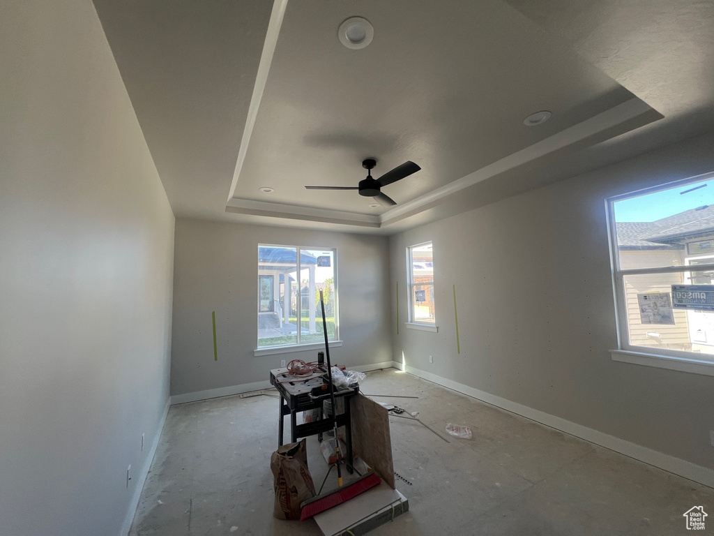 Unfurnished room featuring baseboards, a ceiling fan, and a tray ceiling