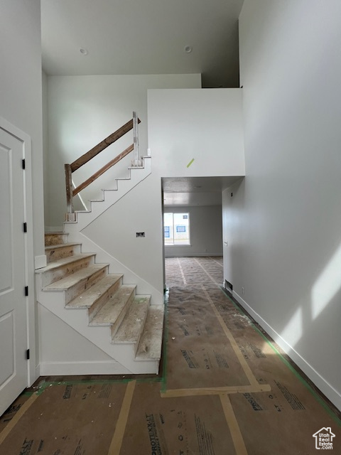 Stairs with baseboards and a towering ceiling