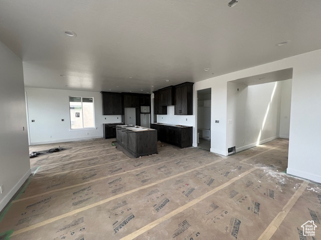 Kitchen featuring open floor plan, baseboards, and a kitchen island