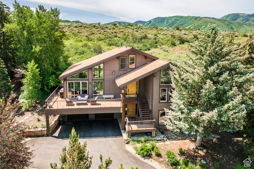 View of front of property with driveway, a deck with mountain view, and stairway