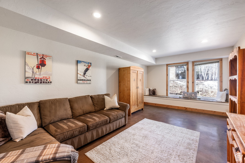 Living room with recessed lighting, baseboards, visible vents, and finished concrete floors