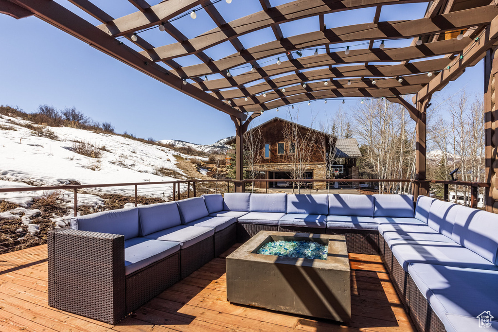 Snow covered deck with an outdoor living space with a fire pit, a mountain view, and a pergola