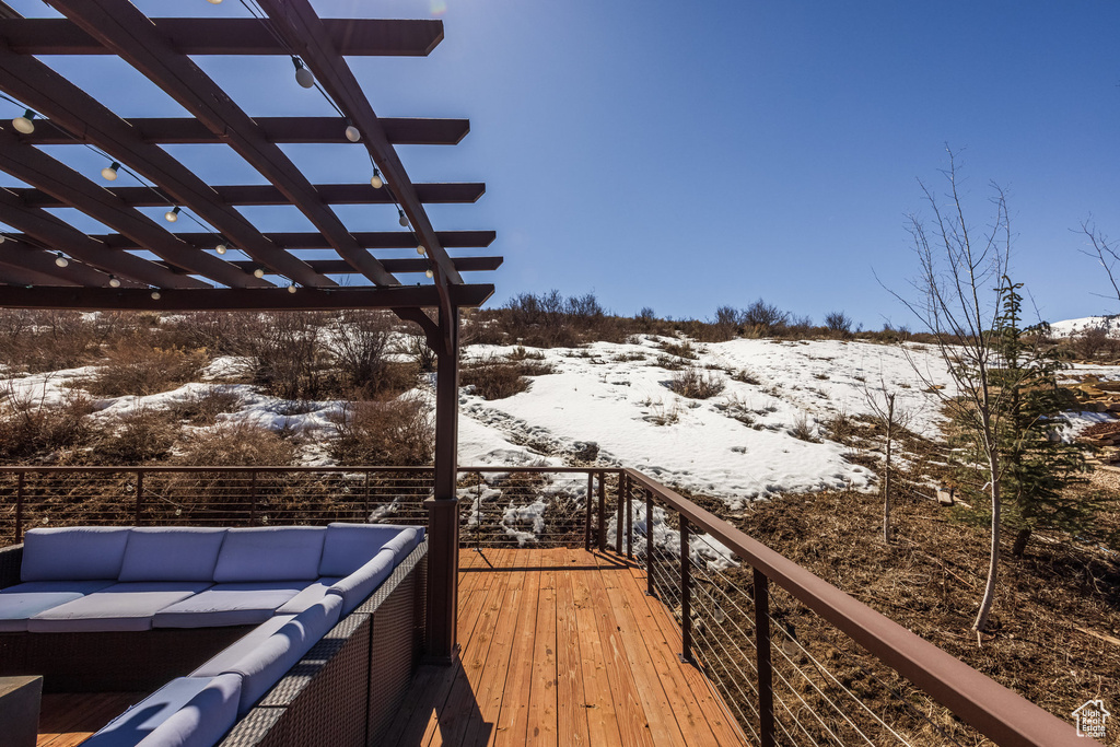 Snow covered deck with a pergola and an outdoor hangout area