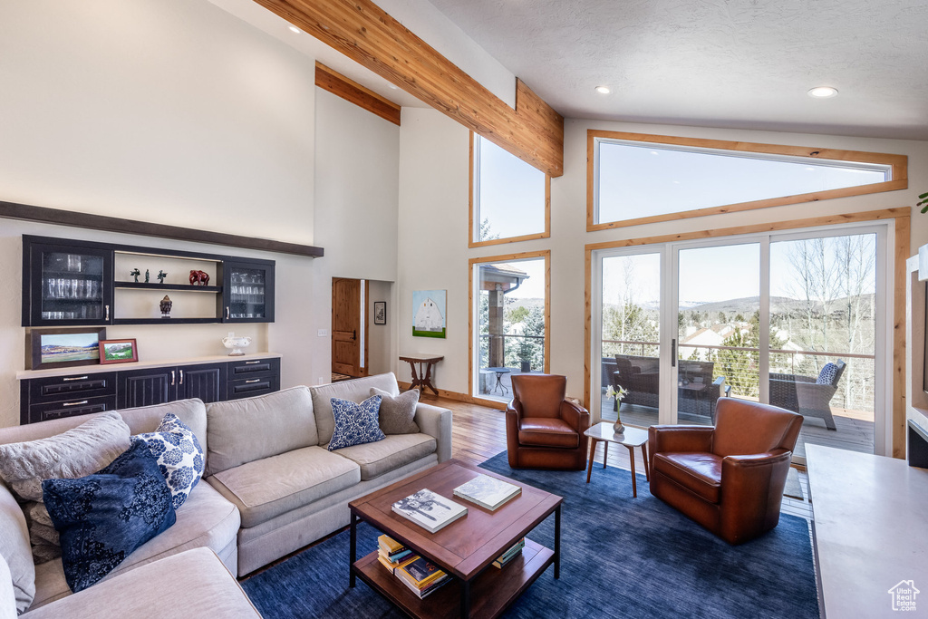 Living area with dark wood-style floors, high vaulted ceiling, recessed lighting, a mountain view, and a dry bar