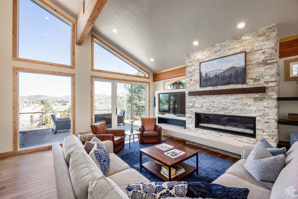 Living area featuring a fireplace, high vaulted ceiling, recessed lighting, beamed ceiling, and hardwood / wood-style flooring