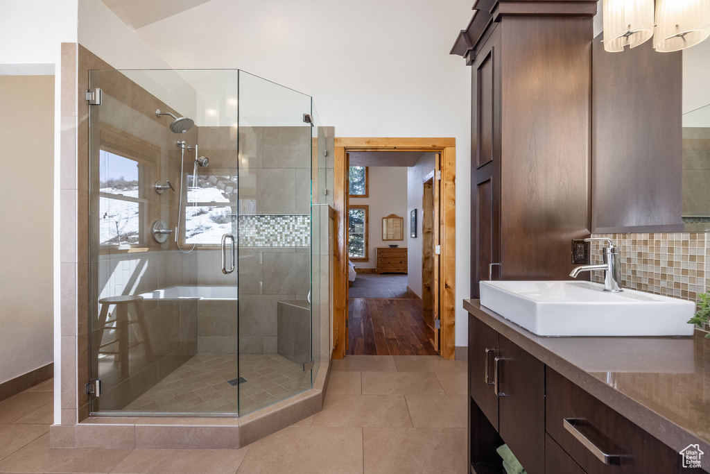 Bathroom featuring vanity, decorative backsplash, baseboards, and a shower stall