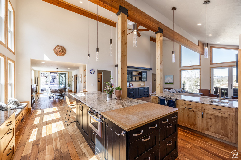 Kitchen with open floor plan, a sink, hardwood / wood-style flooring, and a towering ceiling