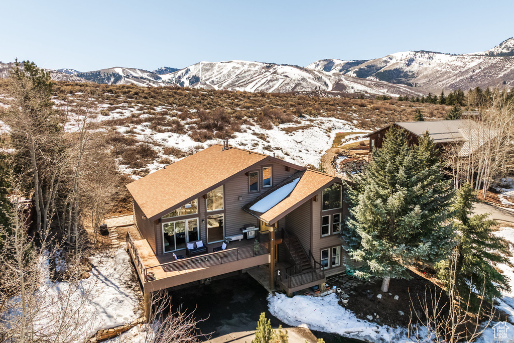 Snow covered back of property featuring a deck with mountain view
