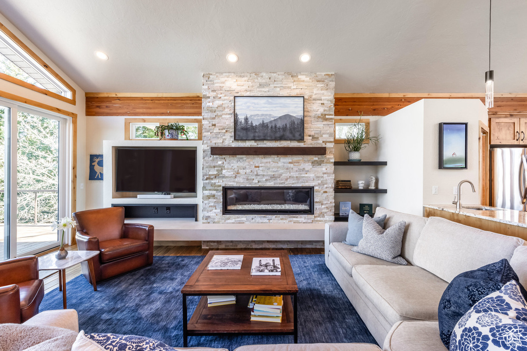 Living area featuring a stone fireplace, recessed lighting, wood finished floors, and lofted ceiling