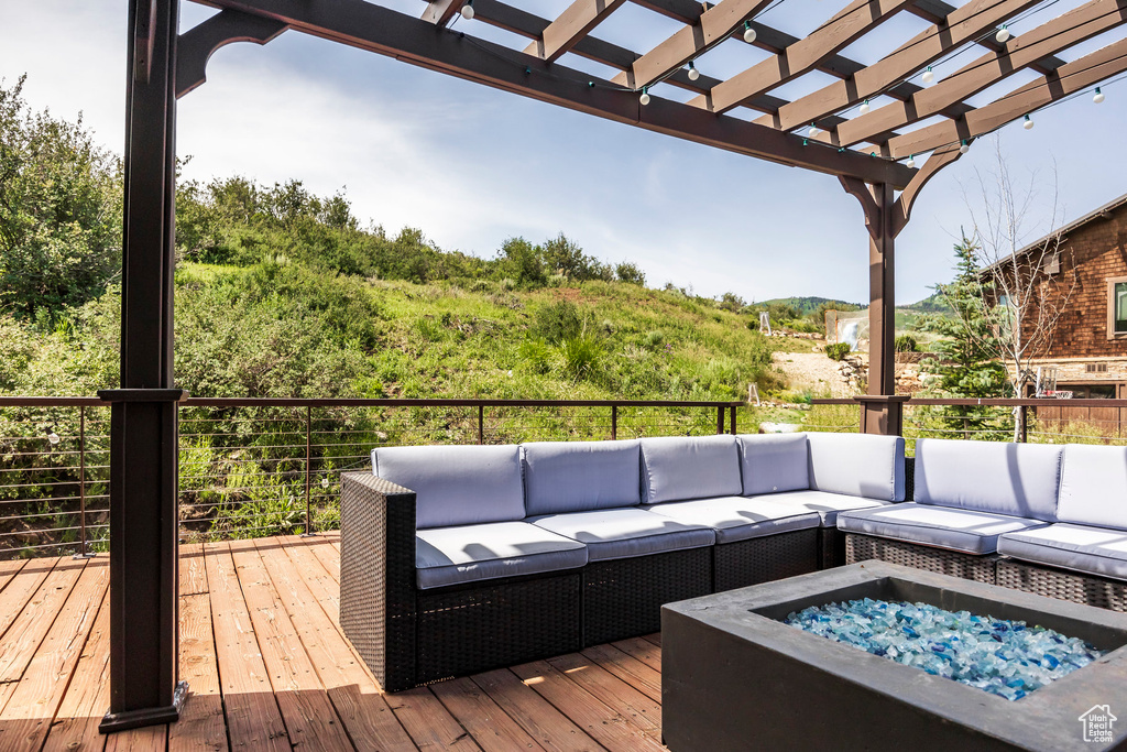 Wooden deck featuring an outdoor living space with a fire pit and a pergola