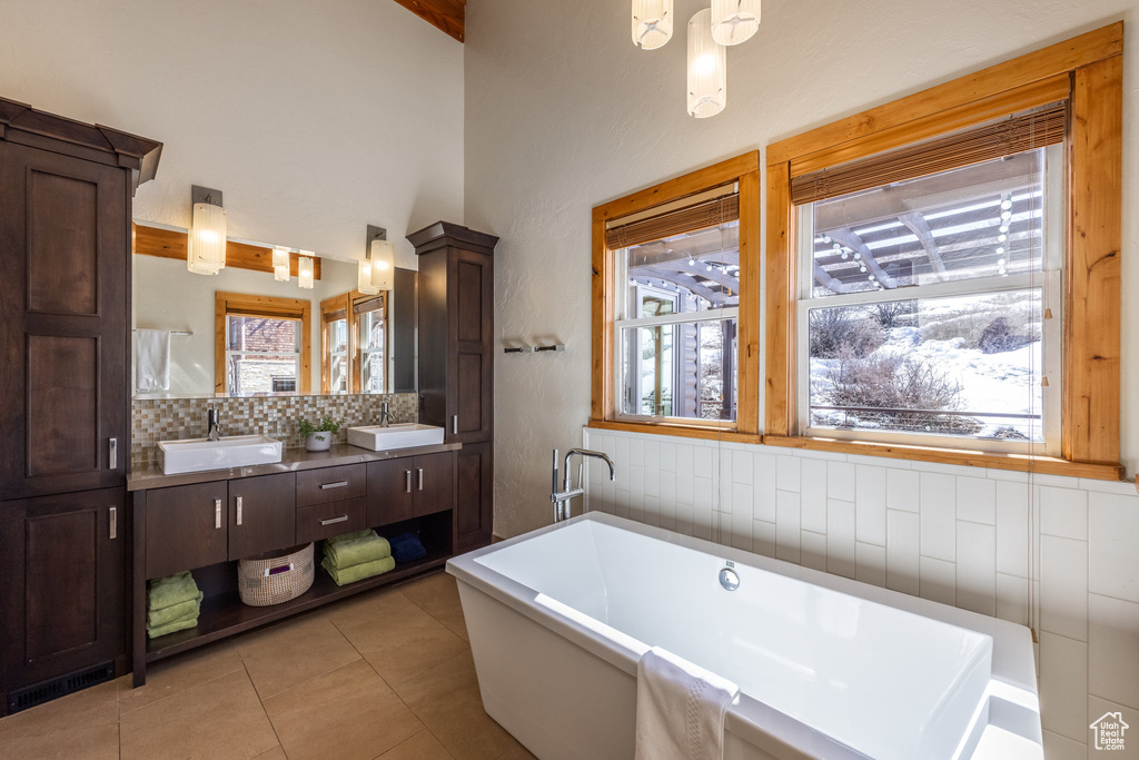 Full bathroom featuring a sink, tile patterned flooring, tasteful backsplash, and a freestanding bath