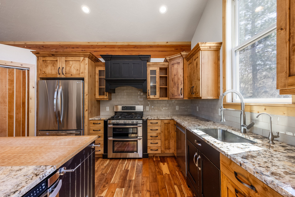 Kitchen with dark wood-style flooring, appliances with stainless steel finishes, a sink, and tasteful backsplash